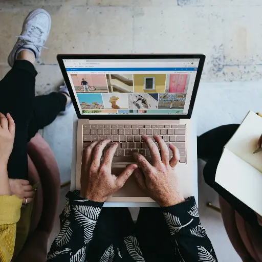 person using microsoft surface laptop on lap with two other people